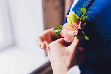 Boutonniere on grooms wedding jacket. White and pink rose wedding boutonniere on suit of groom.