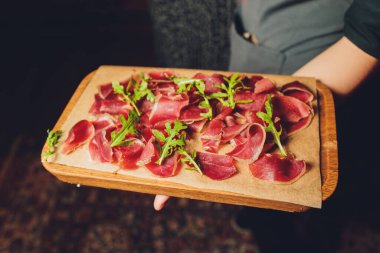 Ahşap tabak meze set tepside kapatın. Soğuk et tabağı dilimlenmiş jambon, salam, pastırma, zeytin ve fesleğen soslu füme. Meze ahşap tepsi testereyle ağaç taklit kesmek. Kopya alanı.