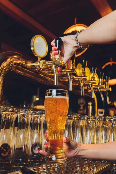 Κοντινό πλάνο ενός αρσενικού μπάρμαν που διανέμει βαρελίσια μπύρα σε μια παμπ κρατώντας μια μεγάλη γυάλινη δεξαμενή κάτω από ένα καρμπυρατέρ πάνω σε ένα βαρέλι από ανοξείδωτο χάλυβα. — Φωτογραφία Αρχείου
