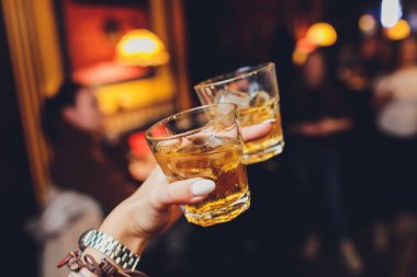 Rye whiskey cocktail drink, on the rocks about to be picked up by a female hand.