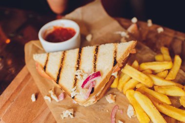 Cheeseburger bitten with french fries and Ketchup on wooden background.