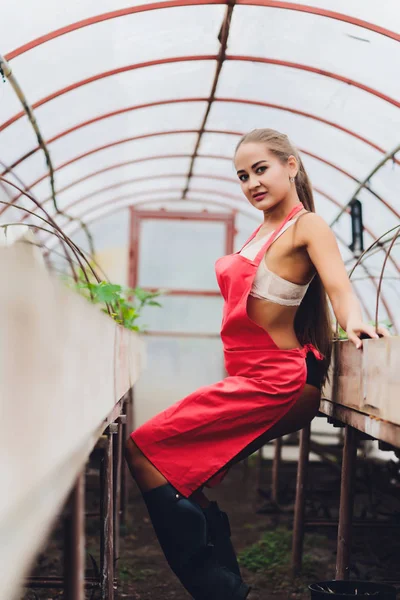 Mooie jonge vrouw tuinieren in een schort, zonder kleren. — Stockfoto