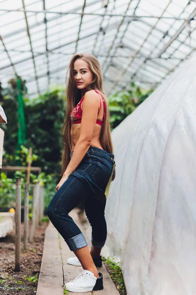 Mooie jonge vrouw tuinieren in een schort, zonder kleren. — Stockfoto