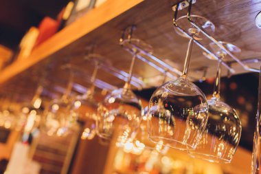 Closeup çok baş aşağı boş şeffaf şeffaf kristal ters şarap bardakları kahverengi ahşap raf, raf, vitrin, paslanmaz çelik korkuluk barda düz sıralar asılı, dolap.