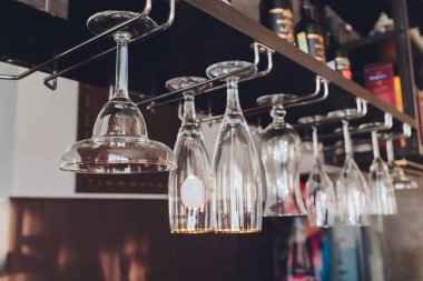 Closeup çok baş aşağı boş şeffaf şeffaf kristal ters şarap bardakları kahverengi ahşap raf, raf, vitrin, paslanmaz çelik korkuluk barda düz sıralar asılı, dolap.