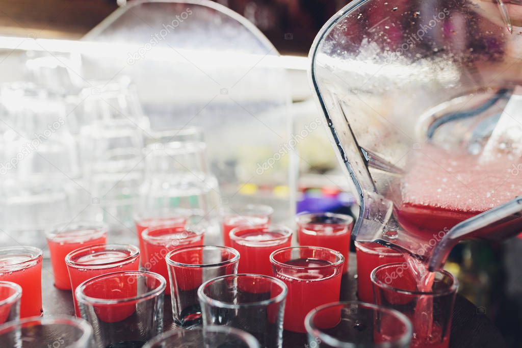 Several red alcohol shots on a bar.