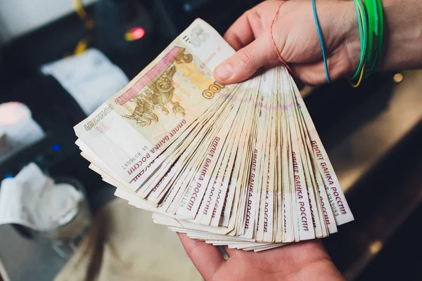 Una foto de cerca de una mano masculina caucásica sosteniendo un billete de 100 rublos rusos. — Foto de Stock