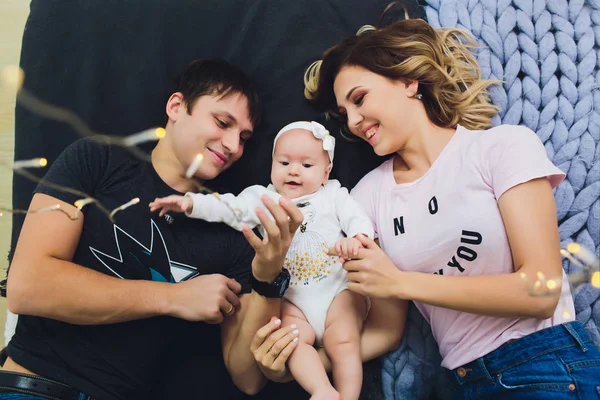 Eltern kuscheln ihr Baby zu Hause im Bett. Mama, Papa und Baby. Glückliches Familienkonzept. — Stockfoto