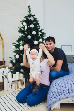 Aile ile Noel ağacının yanında oturan bebek oturur, Bebek bir yıl önce alınmış ve genç bir kadın ve bir adam Noel için bekliyor.