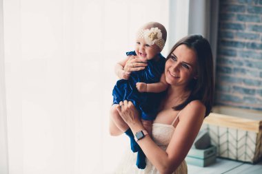 mom holds her lovely child tender standing in a room.