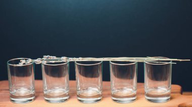 Five empty shot glasses placed symmetrically. Conceptual, commercial and advertising photo. Copy space.