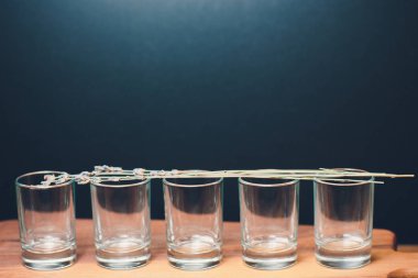 Five empty shot glasses placed symmetrically. Conceptual, commercial and advertising photo. Copy space.