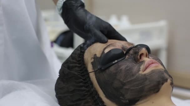 Woman in black mask on procedure carbon laser peeling. — Stock Video