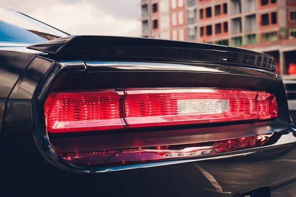 Λεπτομέρεια κόκκινου επιμεταλλωμένου μαύρου πίσω φαναριού αυτοκινήτου σε σχήμα ματιού, με αντανάκλαση ήλιου στην κόρη. — Φωτογραφία Αρχείου