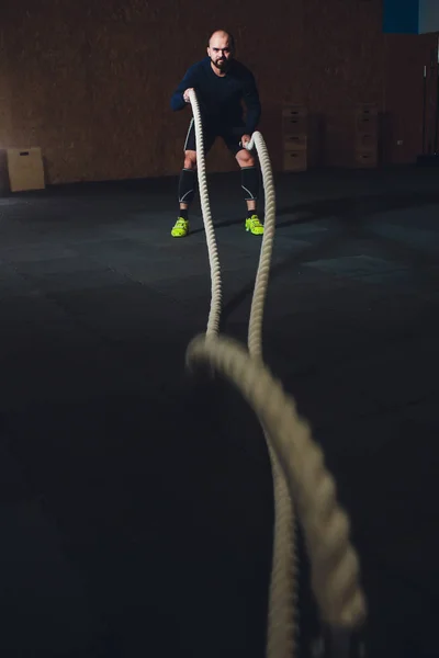 Entraînement cross fit. Homme travaillant avec des cordes de combat à la salle de gym . — Photo