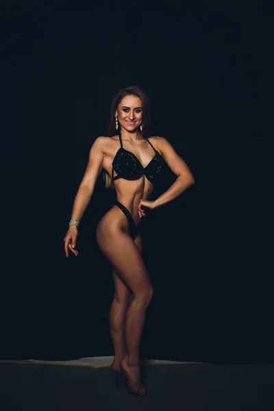 Mujer joven atlética muscular en traje de baño de color sobre fondo negro. Fitness. Cuerpo muscular. Torso. Músculos abdominales —  Fotos de Stock