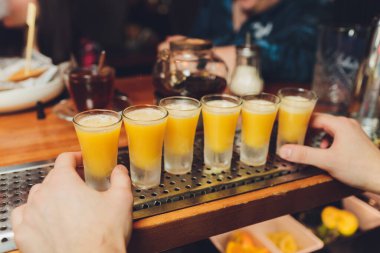 Sıcak ev tatili konsepti. Lezzetli alkolikler meyve suyu içer. Adam bir yudum içki alıyor. Turunçgil meyvesi mandalina kırmızısı, sarı alkollü meşrubat suyu. - Yakın çekim. Hafif arkaplan.