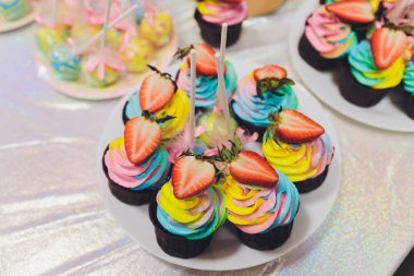 Colorful birthday cupcakes on white wooden table, flat lay.