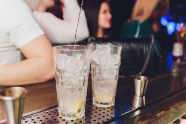 Barmen kokteyl yapar. Bulanık bir barın arka planında dört kokteyl. Barmen kokteyli kırbaçladı. Bulanık çubuk. Mor arka plan. Boşluk. Yatay fotoğraf.