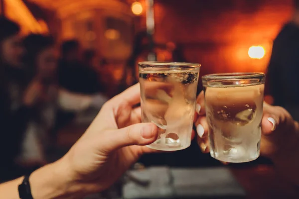 Close up of girls drinking cocktails in nightclub. Girls having good time,cheering and drinking cold cocktails, enjoying friendship together in bar, close up view on hands.