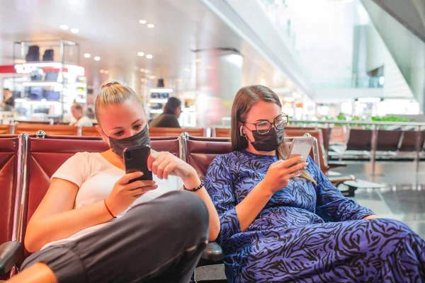 戴着医疗面罩的女人坐在机场，手里拿着电话。中国的考罗纳威。流行病的威胁。空间的副本. — 图库照片