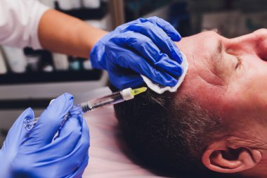 Doktor, hastanın yüzüne iğne yapmak için bir nokta çizer. biyo-evitalizasyon hazırlığı kapat.