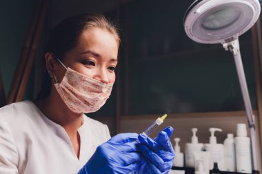 Doktor, hastanın yüzüne iğne yapmak için bir nokta çizer. biyo-evitalizasyon hazırlığı kapat.