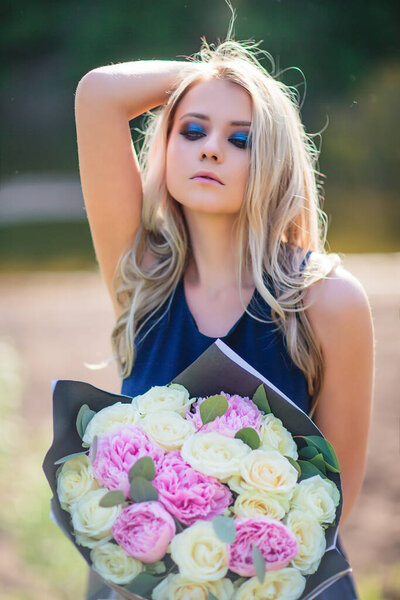 Stunning blond woman holding a bouquet of roses.