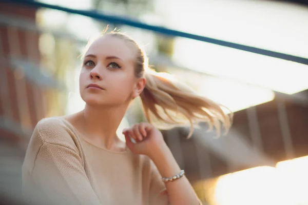 Portret van een vrolijke glimlachende vrouw die op het plein staat op zonnige zomer- of lentedag buiten, schattige lachende vrouw die naar je kijkt, aantrekkelijk jong meisje dat geniet van de zomer, gefilterd beeld, zonnevlam. — Stockfoto