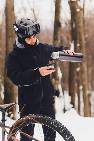 男は魔法瓶からお茶を注ぐ。冬の森。閉鎖. — ストック写真