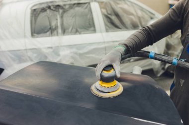 Otomatik tamirci güç tampon makinesi ile cilasını uygulayarak arabayı boya işi için hazırlıyor