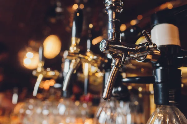 The bar counter with bottles and apparatus for dispensing beer. Apparatus for dispensing beer at the bar. Pub. The bar in the restaurant. Apparatus for dispensing beer in a restaurant.