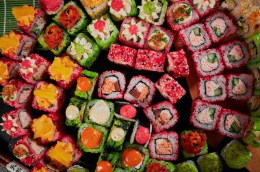 Geleneksel Japon yemekleri - suşi, rulo ekmek ve siyah arka planda sos. Üst görünüm.