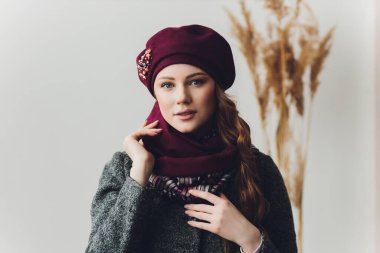 Yana doğru heyecan arayan sürpriz mutlu güzel kadın. Örme sıcak şapka ve gri arka plan üzerinde izole eldivenler giymiş Noel kız.