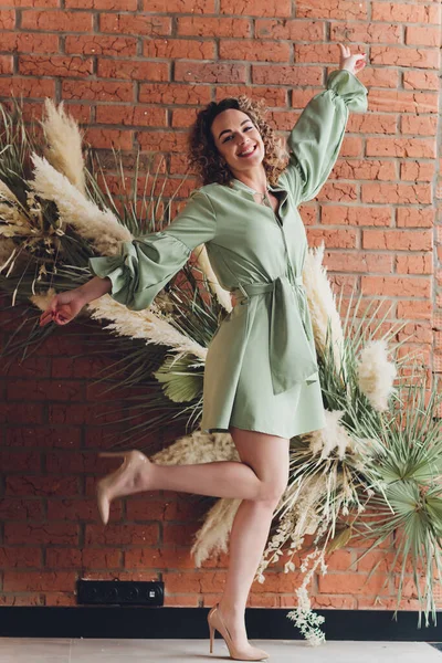 Imagem de jovem ruiva bonita em vestido verde de pé com os braços cruzados sobre fundo de parede cinza. Câmera olhando . — Fotografia de Stock