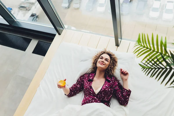 Mujer en la cama del hotel que cubre uno mismo con la hoja . —  Fotos de Stock