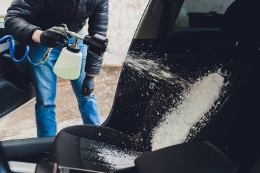 İçini köpük kimyasallar ve fırçalama makinesi kullanarak temizleyen bir adam.