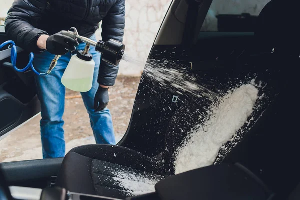 İçini köpük kimyasallar ve fırçalama makinesi kullanarak temizleyen bir adam.