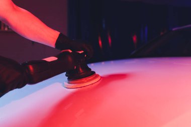 Yörüngesel cilalayıcısı olan bir adam tamir atölyesinde araba parlatıyormuş. Seçici odak.