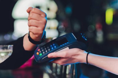 Modern mağaza, NFC teknolojisinde, akıllı saat bağlantısız terminal ile kredi işlemleri ile ödeme yapan genç müşteri erkek elini kapatın.