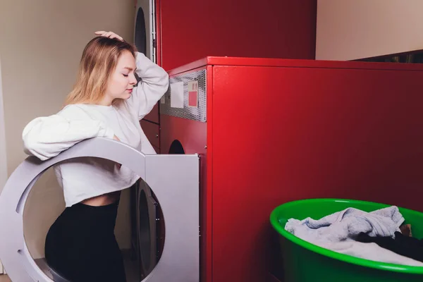 Молодая женщина нажимает кнопки на стиральной машине в химчистке . — стоковое фото