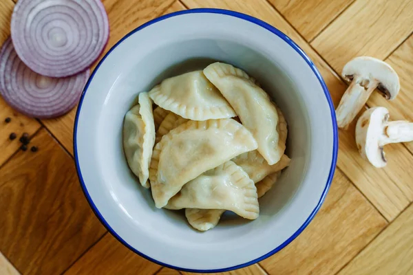 Fervido preparado caseiro pelmeni russo, bolinhos, ravioli com carne em prato cinza com salsa fresca, pimenta, fundo rústico de madeira. Vista superior . — Fotografia de Stock