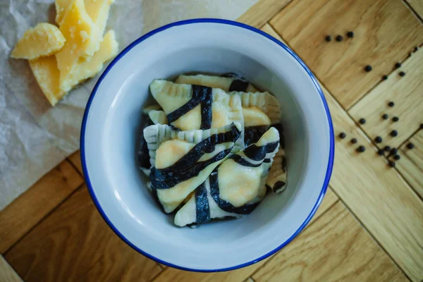 Fervido preparado caseiro pelmeni russo, bolinhos, ravioli com carne em prato cinza com salsa fresca, pimenta, fundo rústico de madeira. Vista superior . — Fotografia de Stock