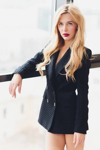 Blonde business woman in a black suit.