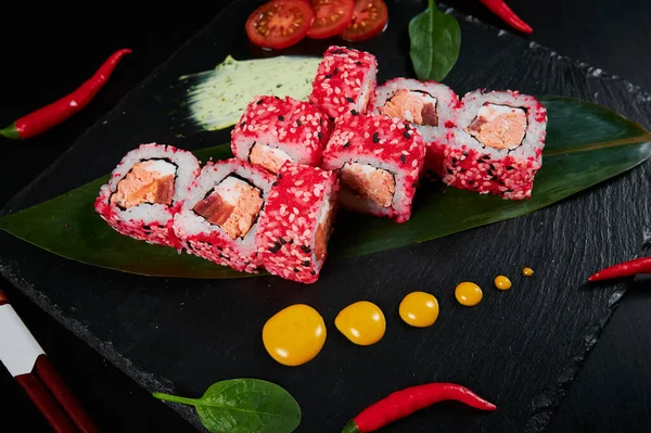 Geleneksel Japon yemekleri - suşi, rulo ekmek ve siyah arka planda sos. Üst görünüm. — Stok fotoğraf