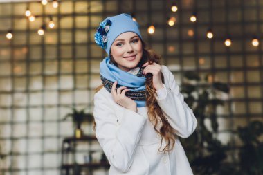 Yana doğru heyecan arayan sürpriz mutlu güzel kadın. Örme sıcak şapka ve gri arka plan üzerinde izole eldivenler giymiş Noel kız.