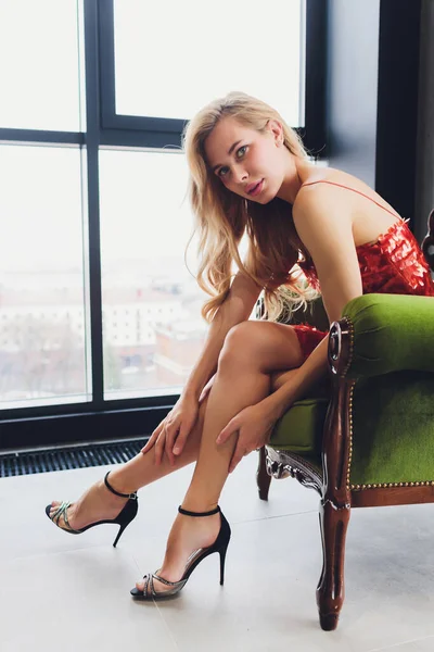 Young beautiful woman sitting in a vintage chair and looking at the camera, relaxed posture. — Stock Photo, Image