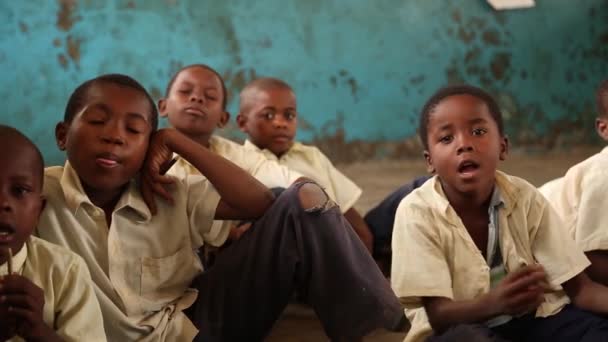 ซานดิเอโก, แทนซาเนีย - 15 กรกฎาคม ค.ศ. 2019: เด็กแอฟริกันที่มีศีรษะโกนหนวด มองขึ้นไปบนดวงตาที่ดูจริงจัง ในโรงเรียนเด็ก — วีดีโอสต็อก