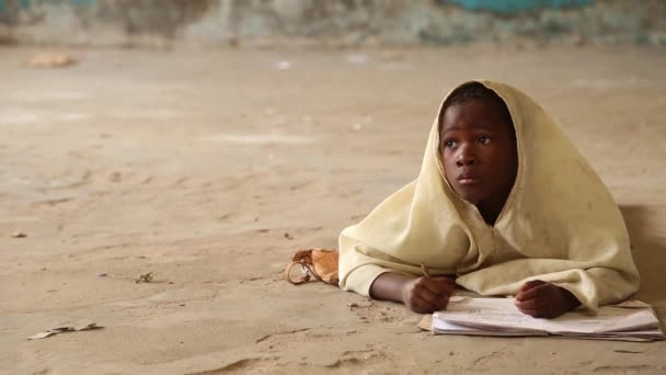 Занзибар, Танзания - 15 июля 2019 года: африканский ребенок с бритой головой смотрит вверх, большие серьезные глаза. в детском саду — стоковое видео