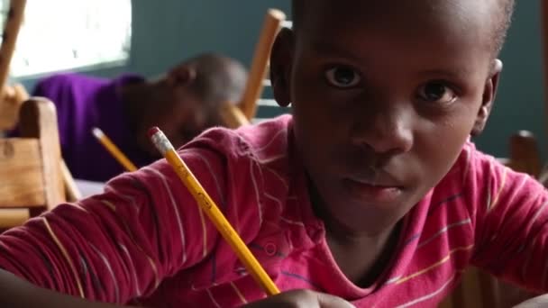 Занзибар, Танзания - 15 июля 2019 года: африканский ребенок с бритой головой смотрит вверх, большие серьезные глаза. в детском саду — стоковое видео